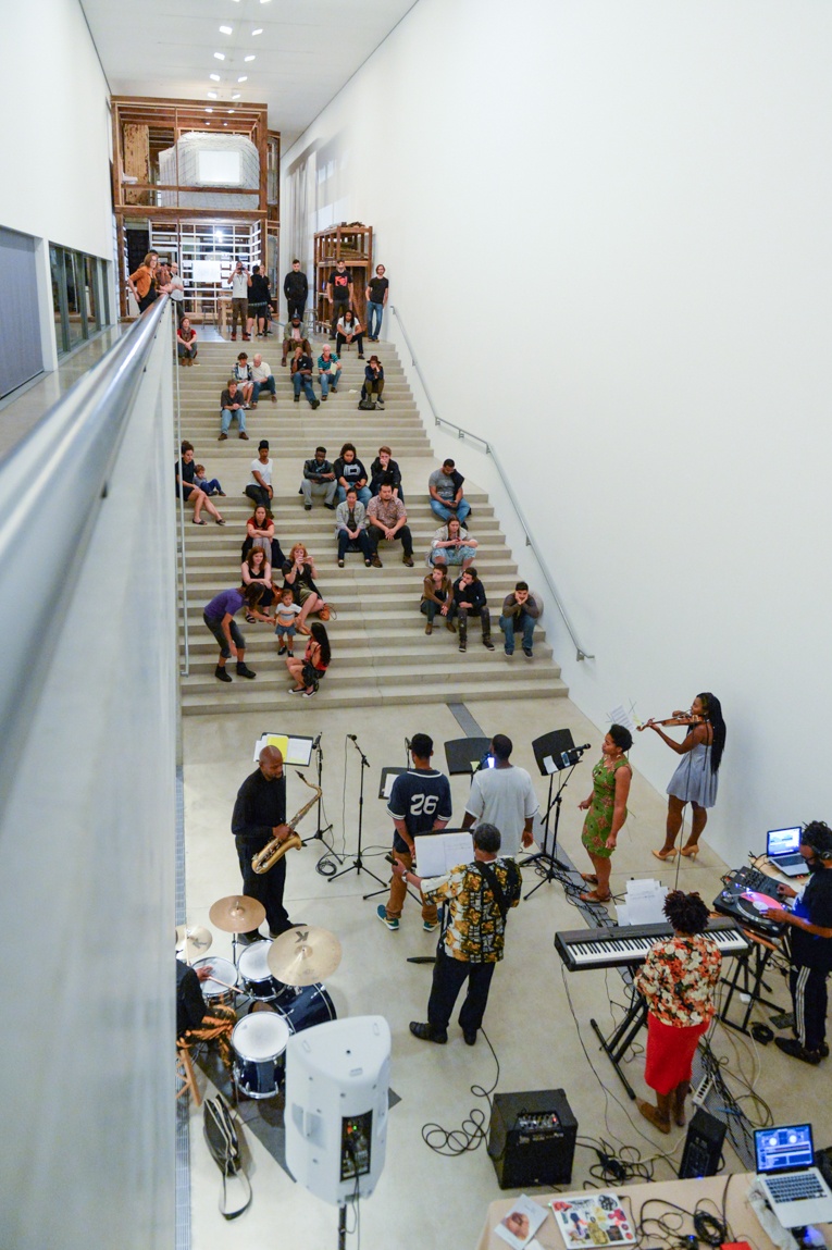 Aerial view of visitors on the Main Staircase and musical performers playing in the Lower-Main Gallery.