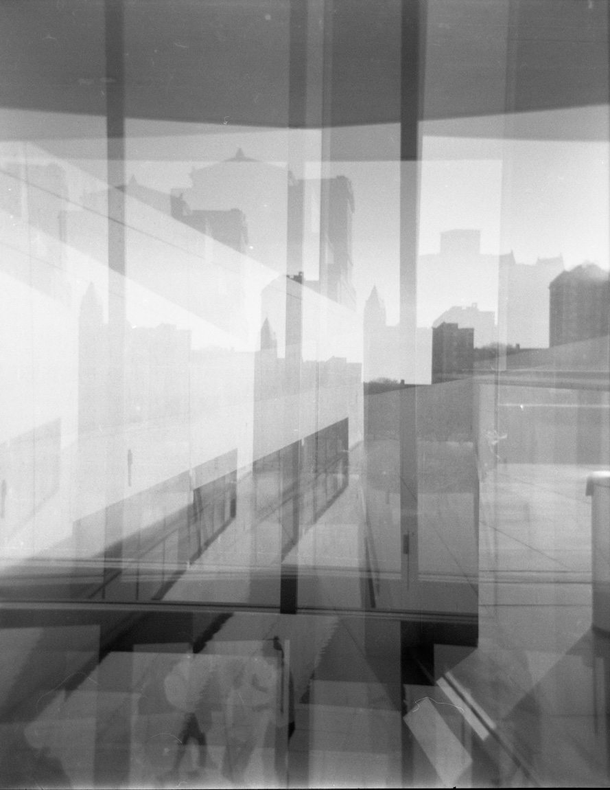 A black and white film photograph of a distorted view through windows at the St. Louis skyline from the Mezzanine.