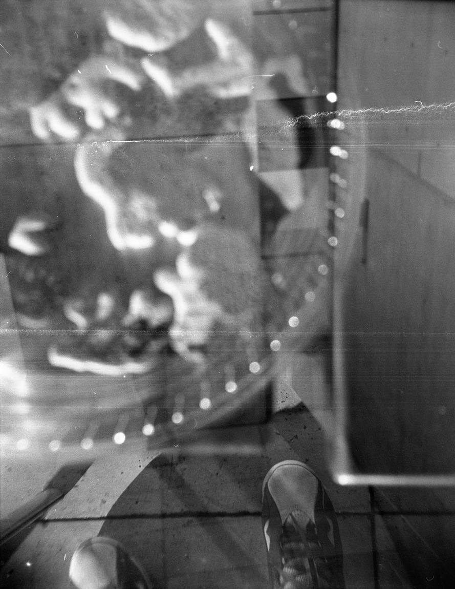 A black and white film photograph of a distorted reflection.