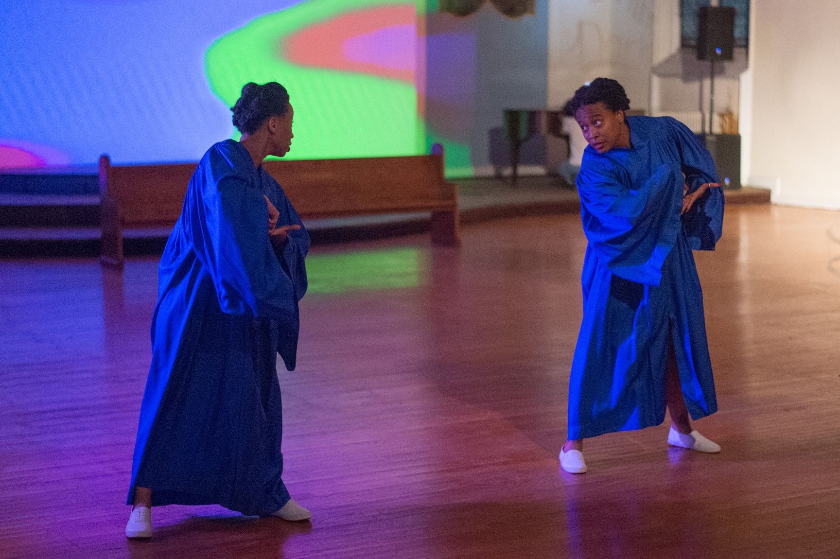 Two AUNTS dancers perform wearing blue choir robes inside the former St. Matthew’s United Church of Christ.