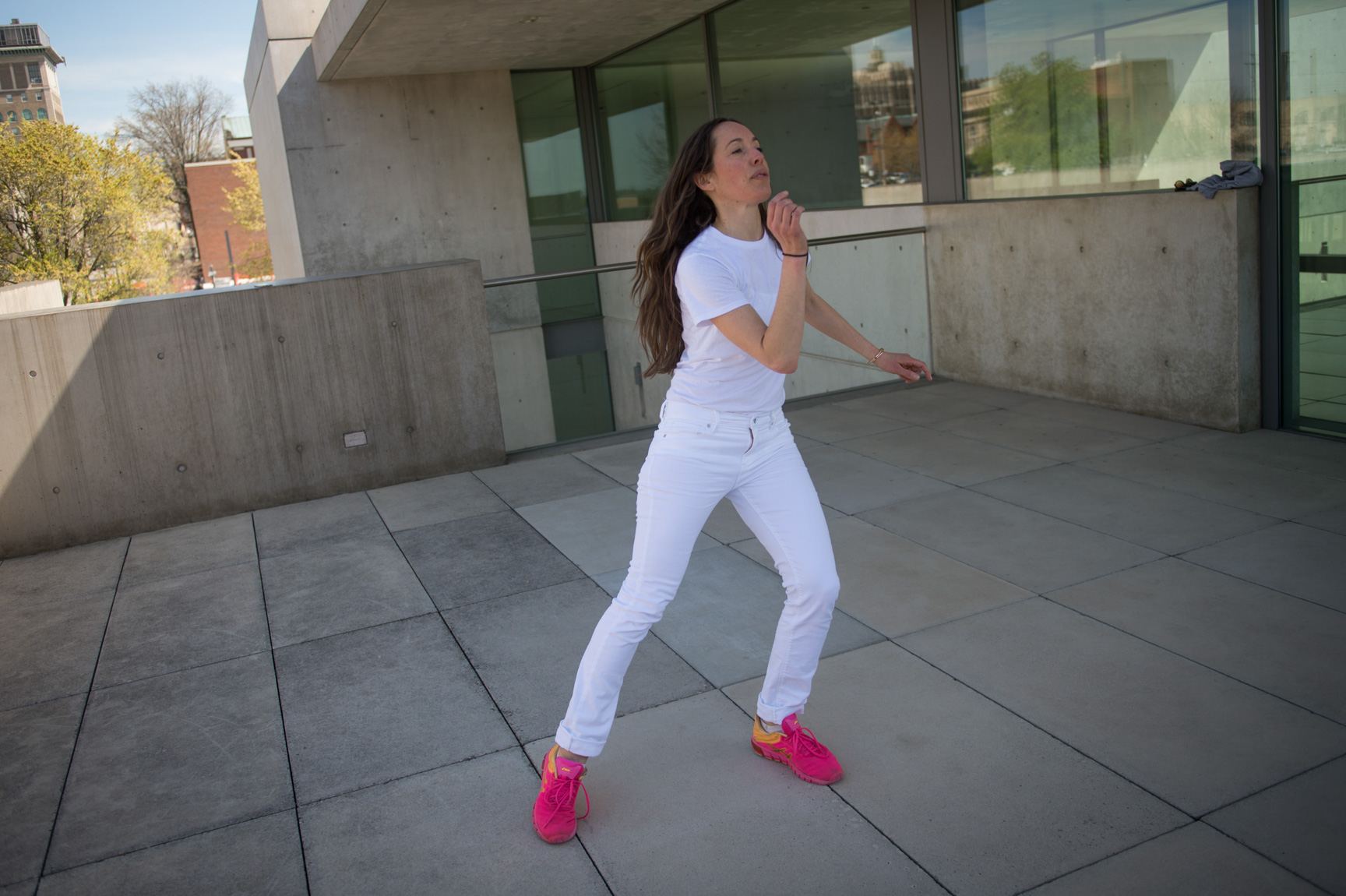 An AUNTS member performs a dance wearing a all white with pink sneakers on the Mezzanine patio.
