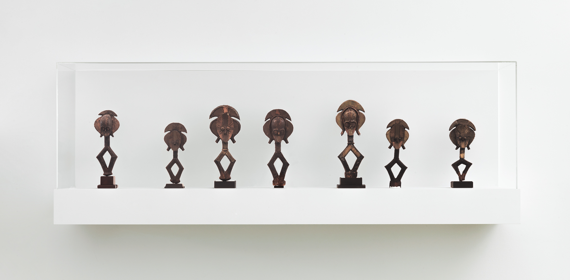 Seven Kota figures are displayed in a wall vitrine.