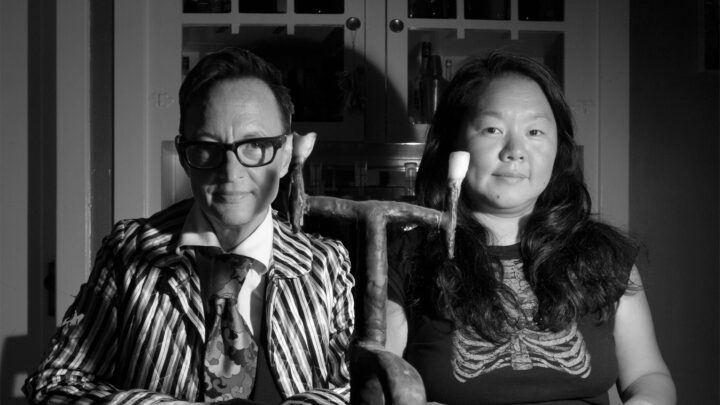 A black and white photograph of Asher Hartman and Haruko Tanaka seated at a table and looking into the camera.