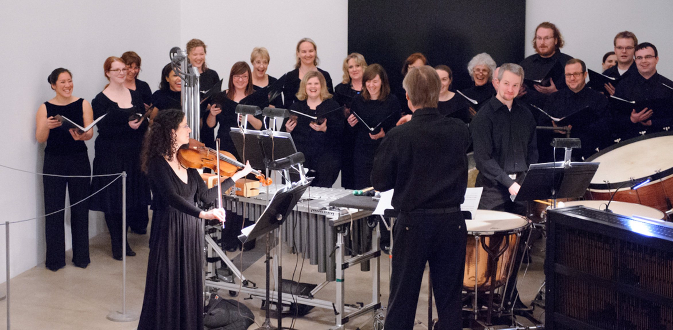 David Robertson conducts musicians and choir singers in the Lower Main Gallery.