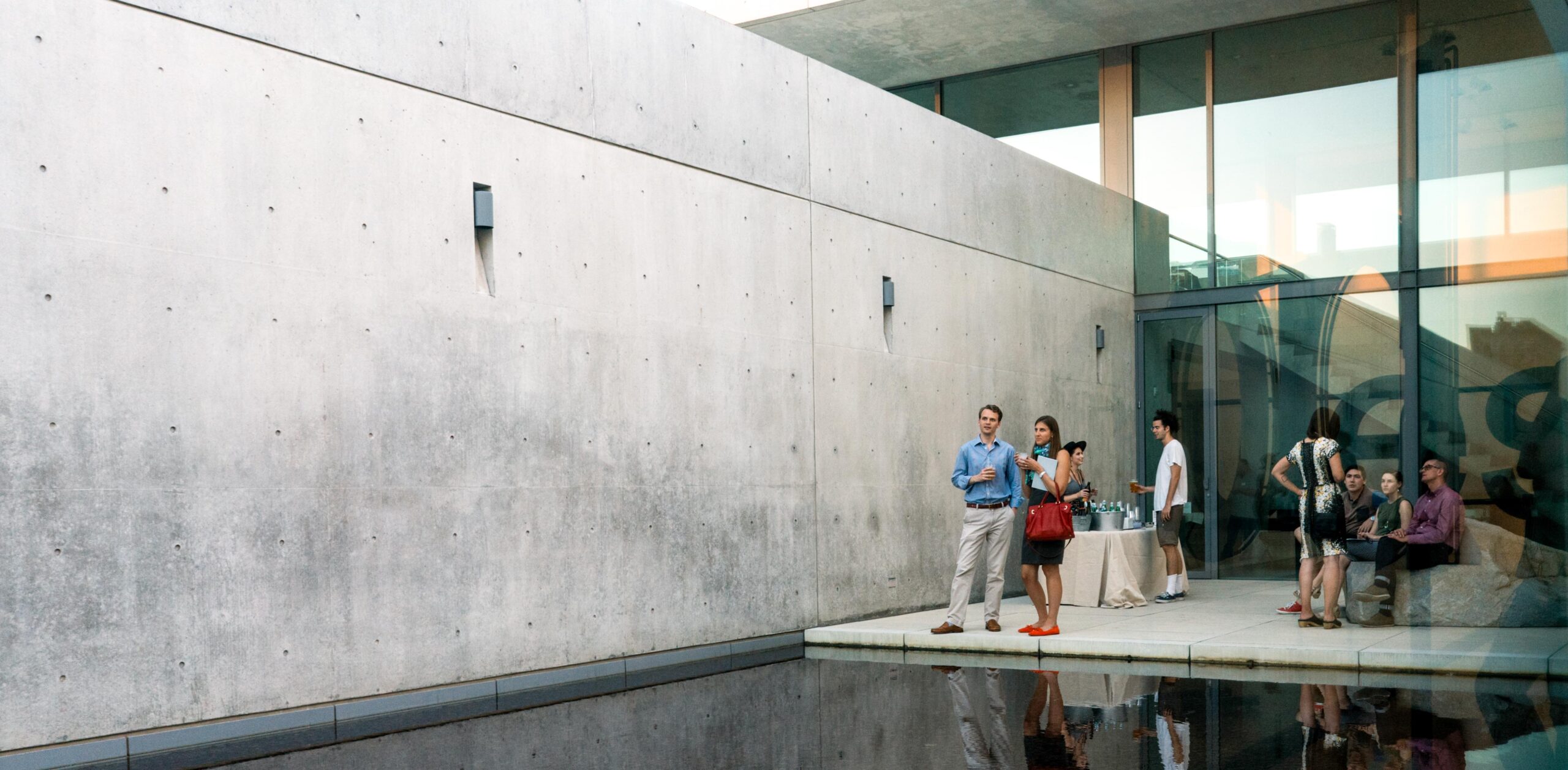 Visitors gather in the Water Court, and a gallery attendant serves drinks at a table.