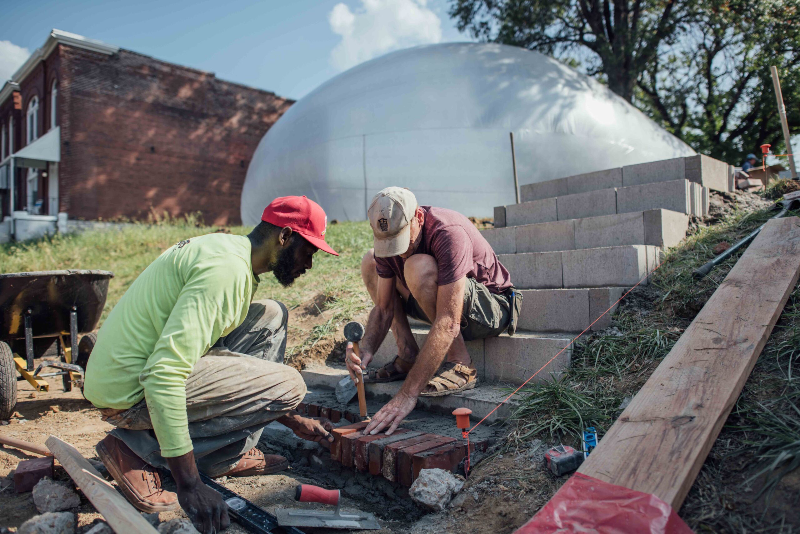 Two participants lay down brick stairs on the lawn, the Spacebuster bubble behind them.