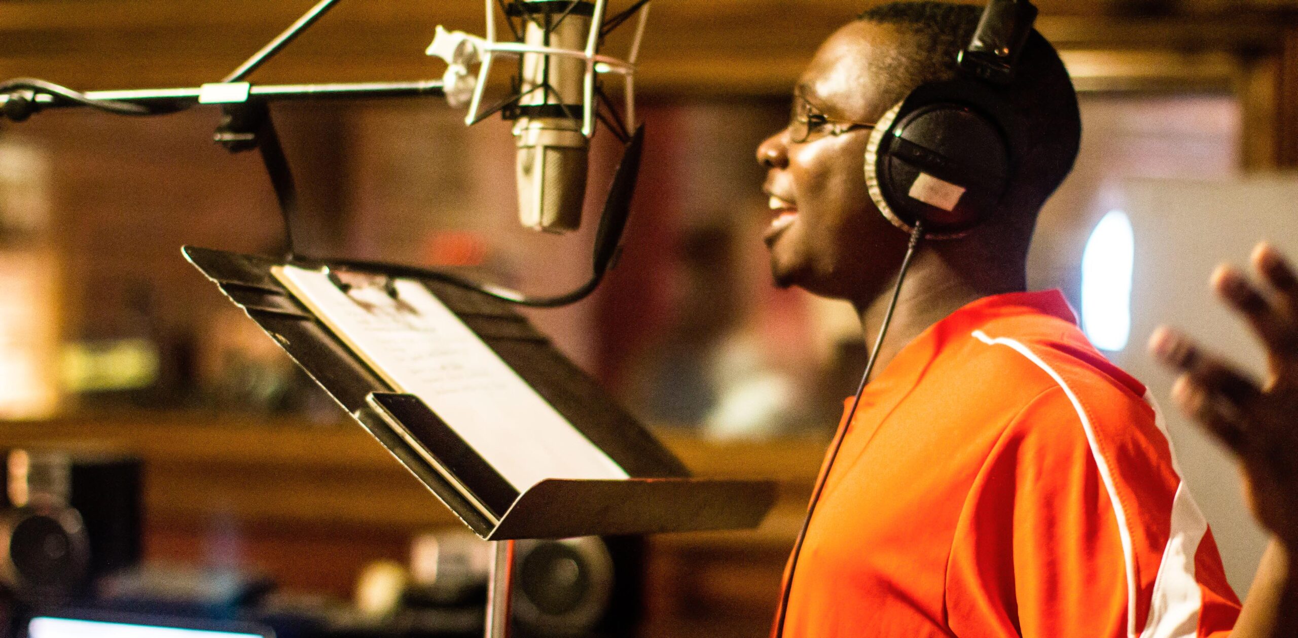 An artist speaks into a microphone in a recording studio.