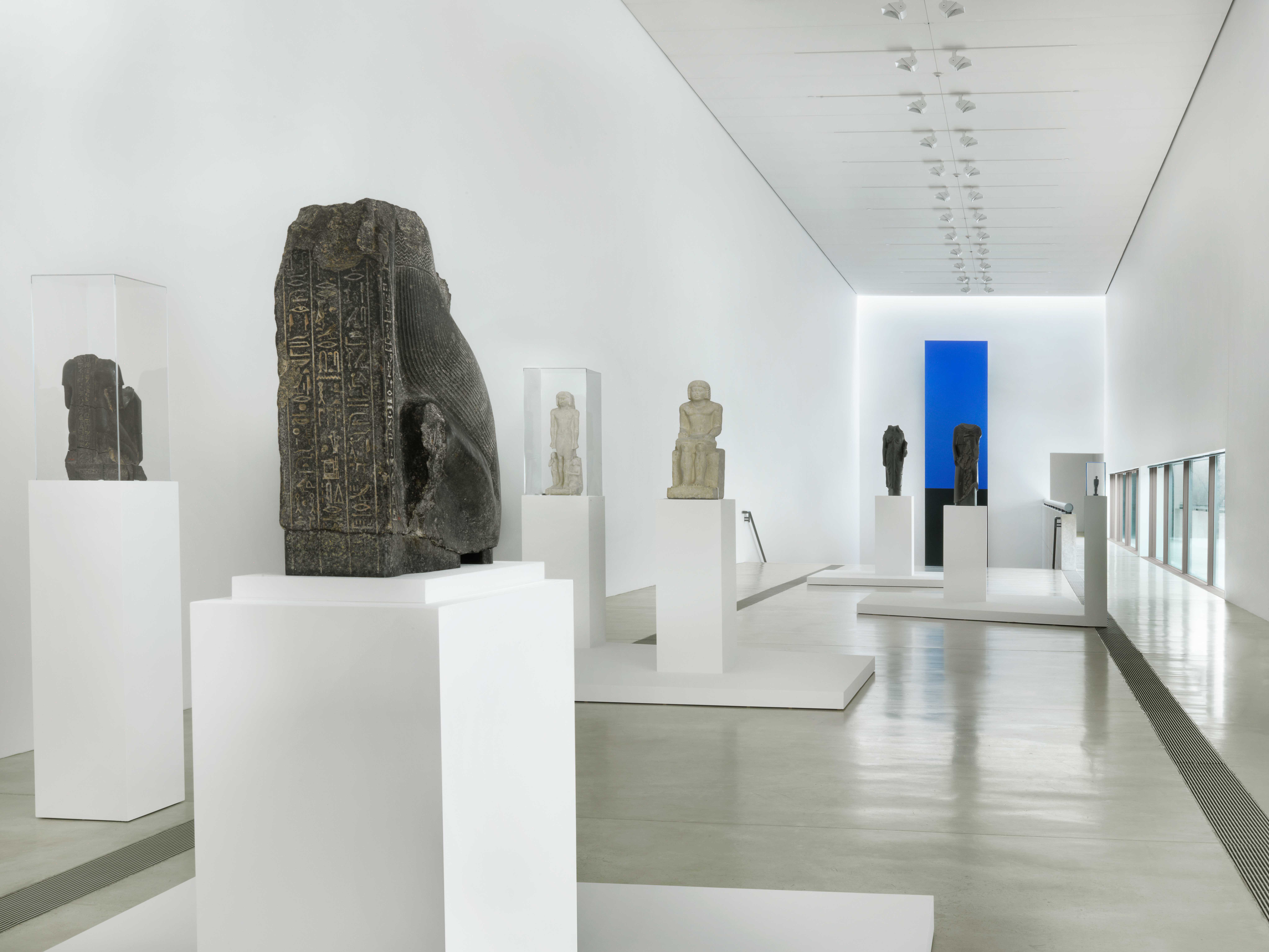 A view of Egyptian sculptures on pedestals and vitrines in the Main Gallery.