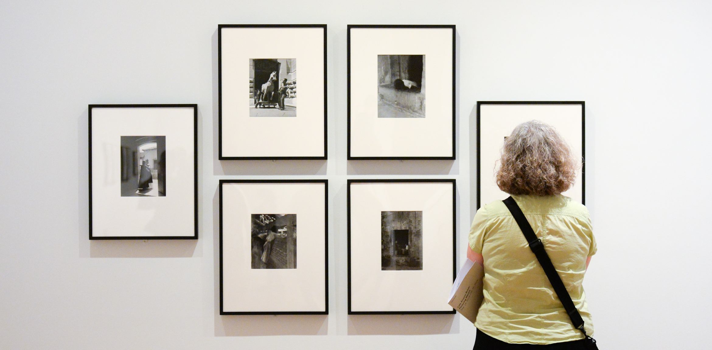 A visitor stands before a wall of Lola Álvarez Bravo's framed photographs.