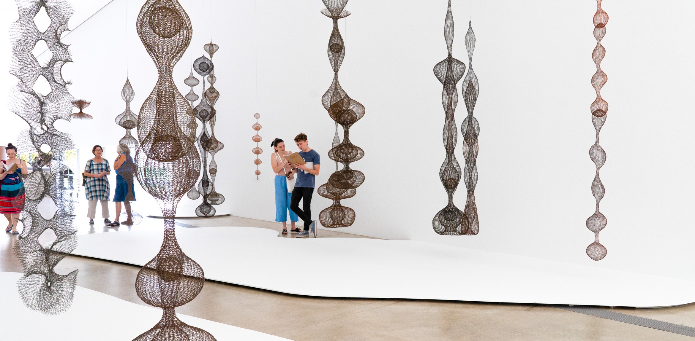 Visitors stand amid Ruth Asawa's hanging wire sculptures in the Main Gallery.