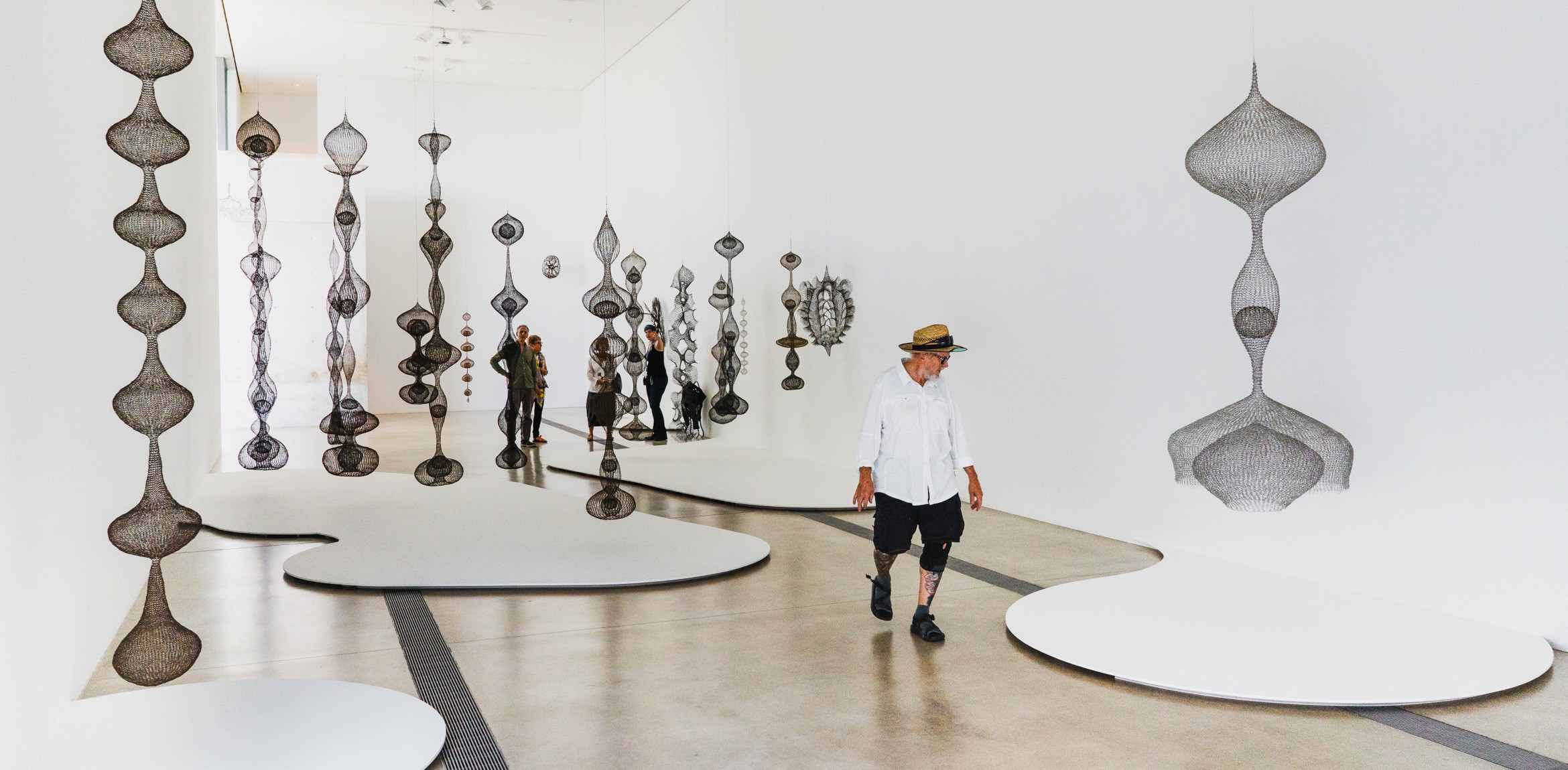 Visitors stand amid Ruth Asawa's hanging wire sculptures in the Main Gallery.