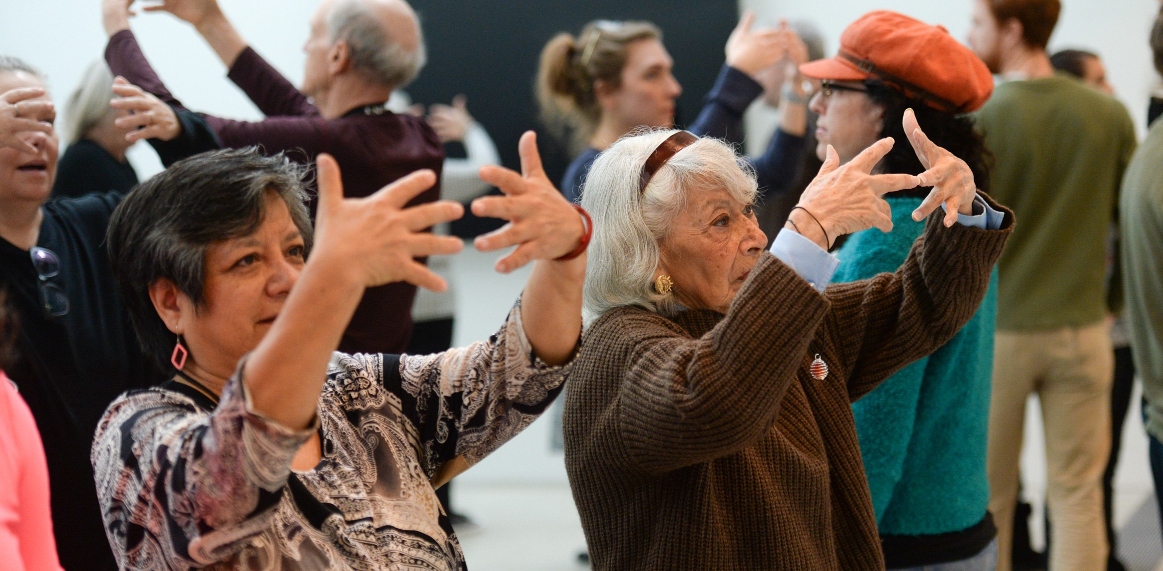 Visitors participate in an exercise, holding their hands up facing themselves.
