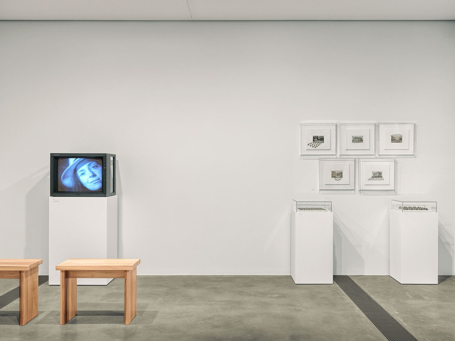 (Left) A monitor on a pedestal with tool stools; (Right) Five framed works and two pedestals