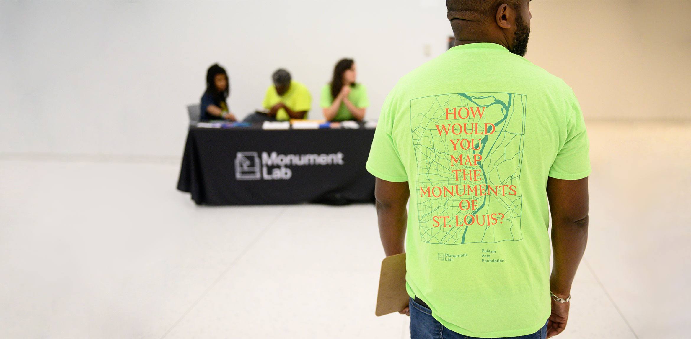 A Monument Lab staff member wearing a neon shirt that reads 