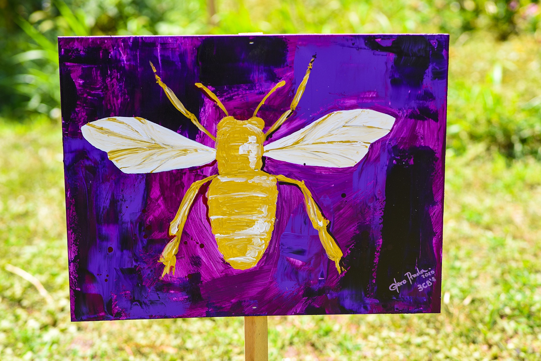 A purple and blue painting of a yellow bee on a post in a grassy field.