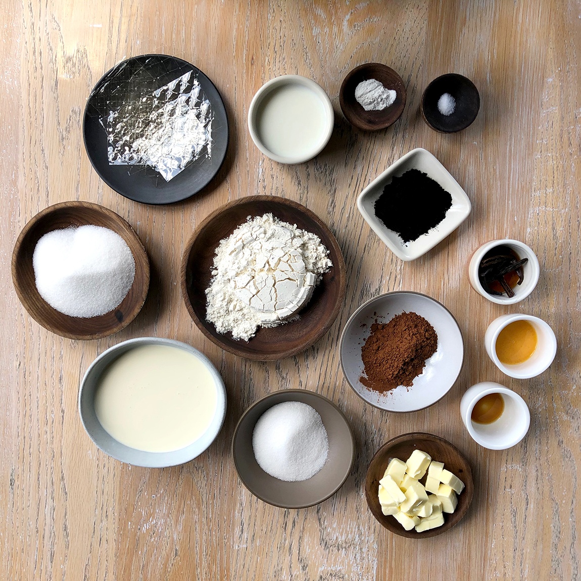An aerial view of the ingredients in separate small bowls on a wood surface.