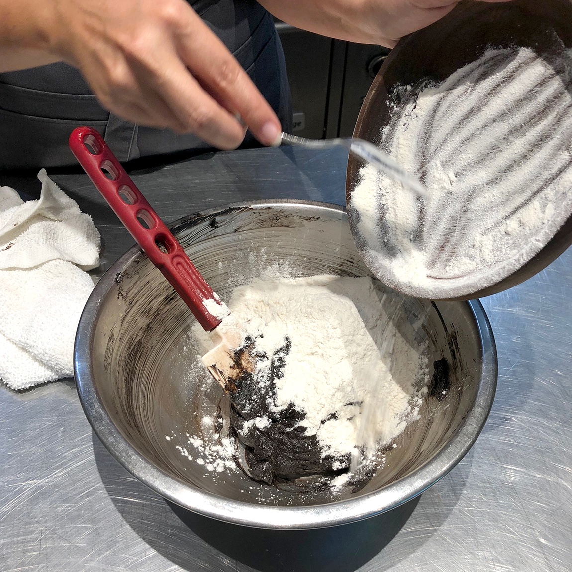 Summer Wright spoons a floury mix into a metal mixing bowl.
