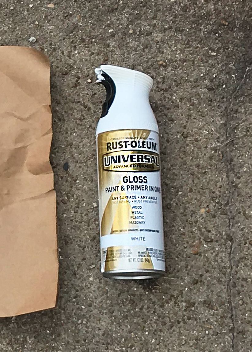 A shot of the Rust-Oleum can of white glossy spray paint, lying on the pavement.