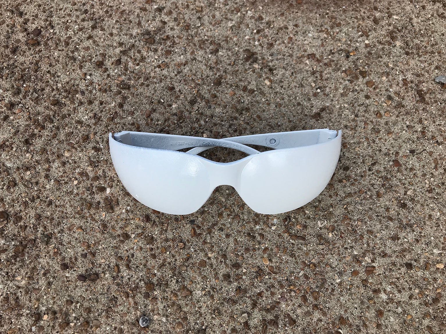 A pair of white listening glasses on a pavement.