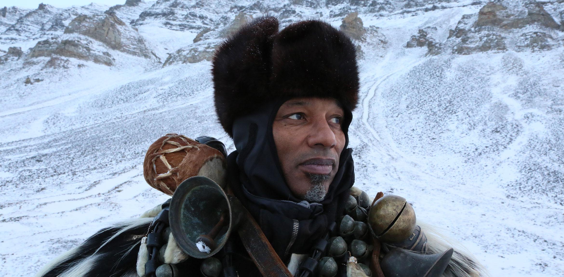 A portrait of Terry Adkins in a snowy landscape, wearing a fur hat with bells wrapped around his shoulders.