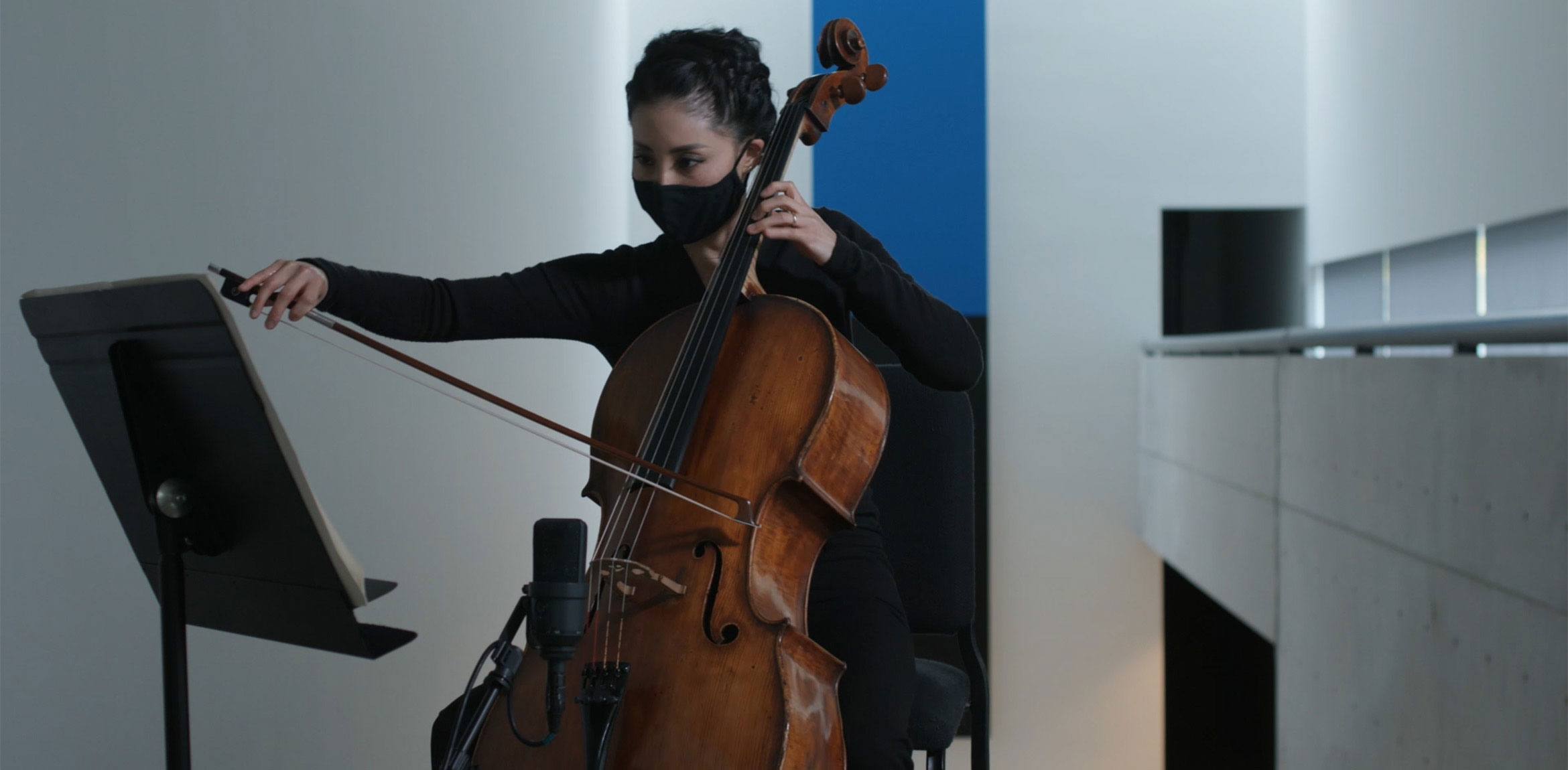 Cellist Elizabeth Chung performs Nathalie Joachim's "Dam Mwen Yo" at the top of the Main Staircase, reading from a music stand. Ellsworth Kelly's "Blue Black" is seen behind them.