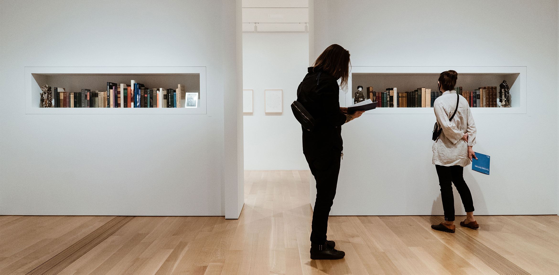 Two visitors view Terry Adkins' personal collection of literature in the Lower East Gallery.