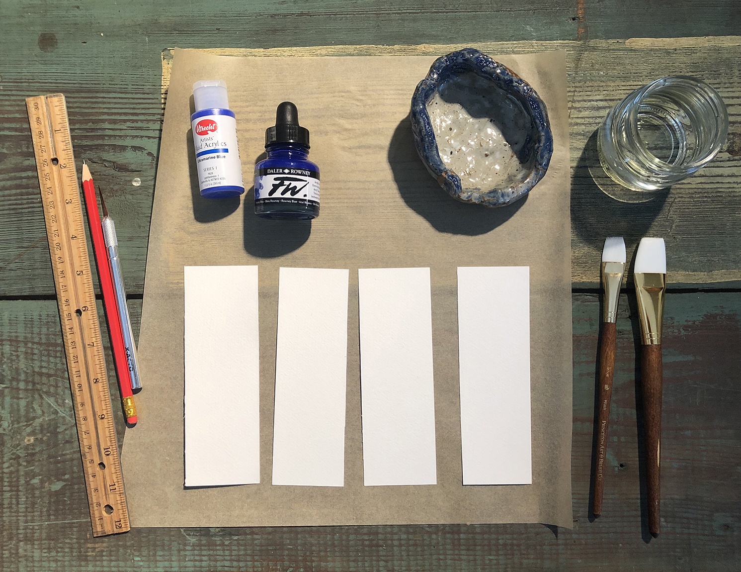 Four white strips of paper, surrounded by supplies for the activity.
