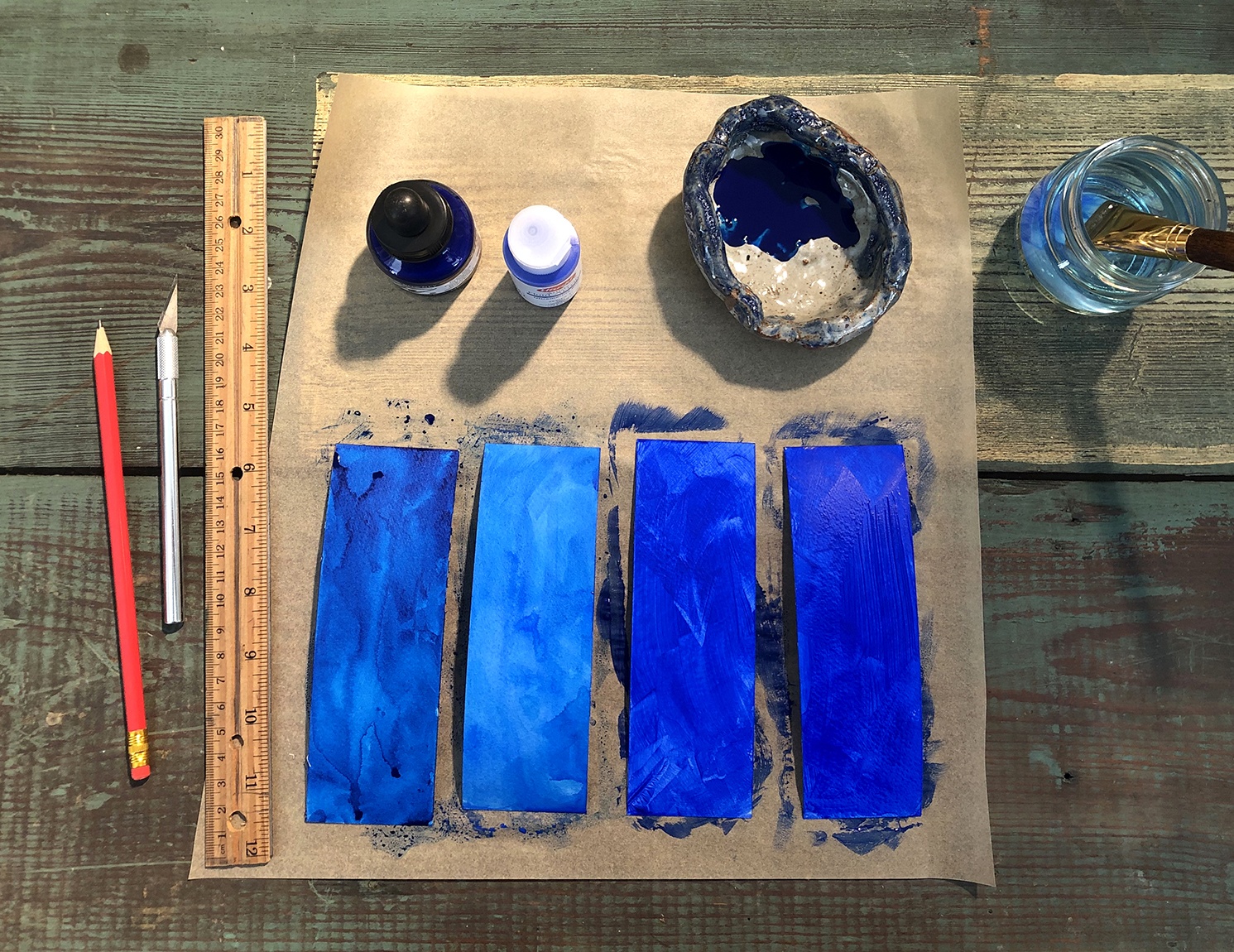 Four strips of ultramarine-painted paper, surrounded by supplies for the activity.