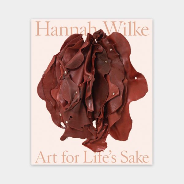 Exhibition catalogue cover of Hannah Wilke: Art for Life's Sake. The cover is a light pink with beige text and features a red latex sculpture by Wilke.