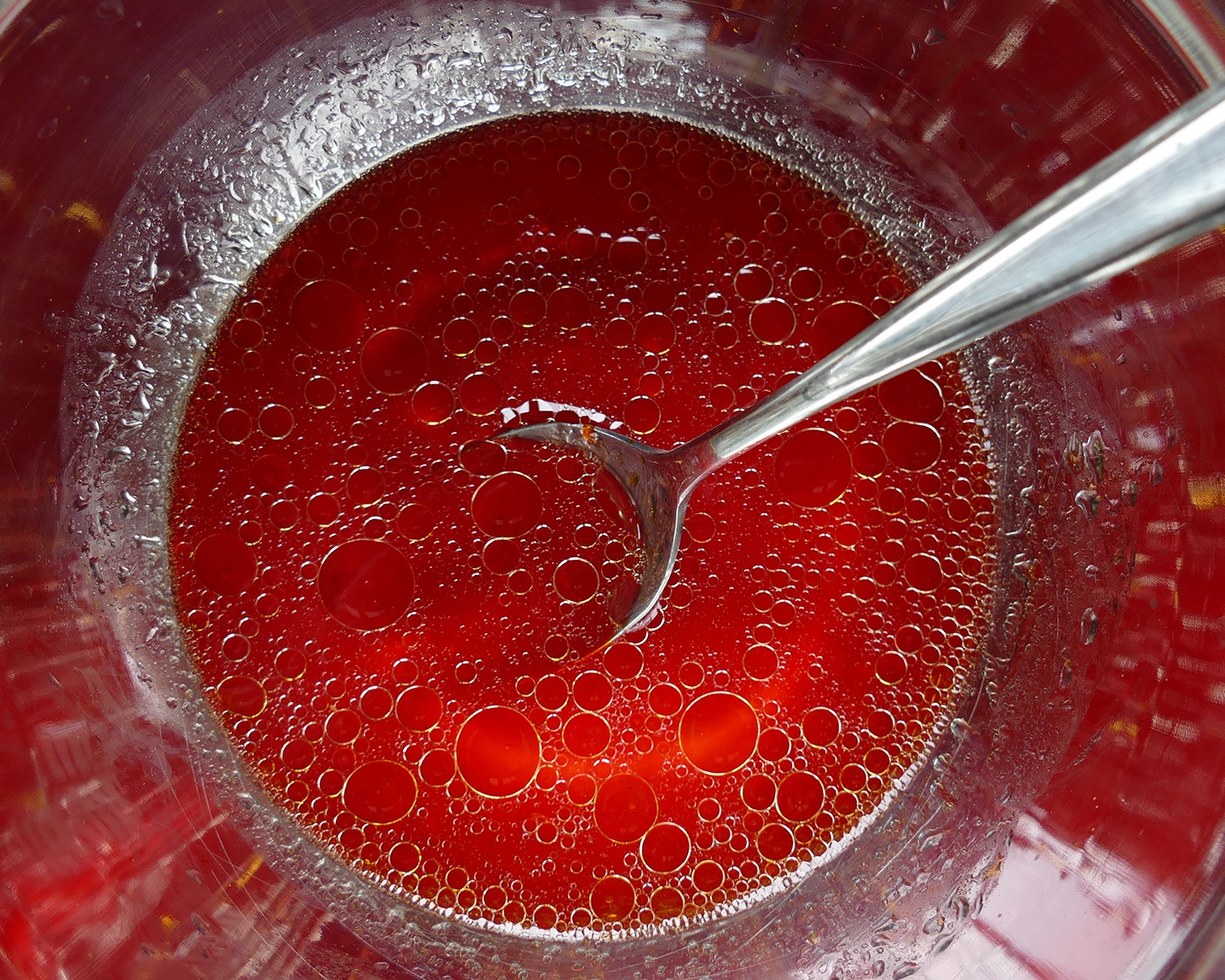 Red liquid in a metal bowl with a submerged spoon