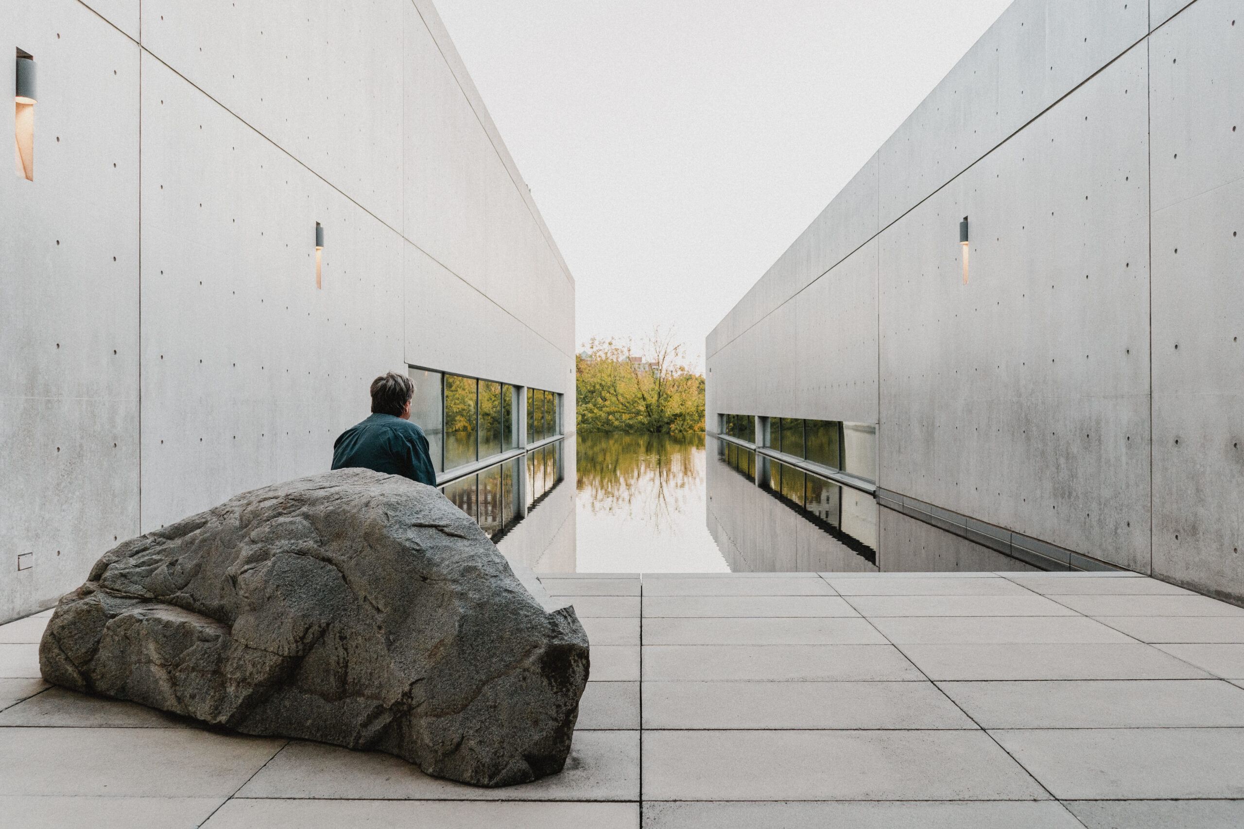 Individual sitting on "Rock Settee" sculpture by Scott Burton in the watercourt of the Pulitzer Arts Foundation