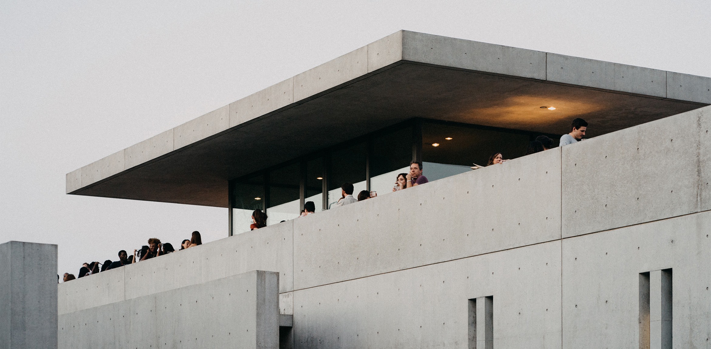 The upper exterior mezzanine of the museum with several event attendees gazing over the ledge