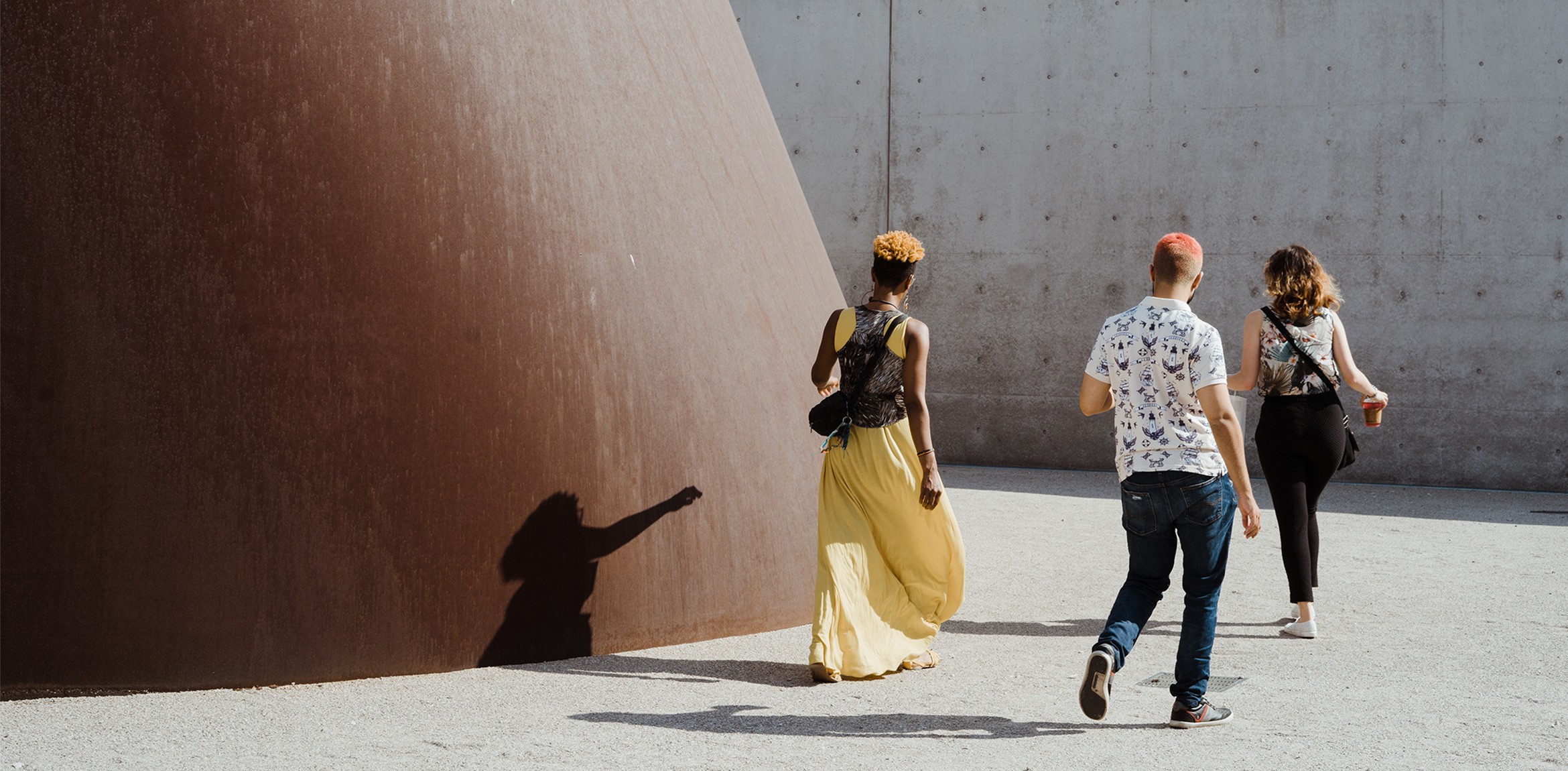 Three visitors walking around the base of Richard Serra's Joe