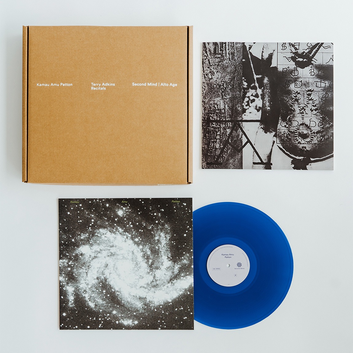 A blue vinyl record, cardboard box, album sleeve, and open publication featuring space imagery