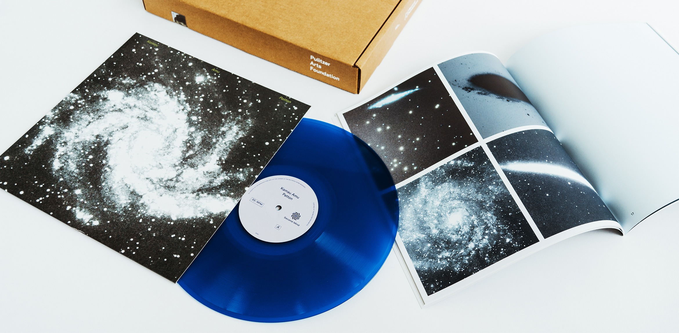 A blue vinyl record, album sleeve, and open publication featuring space imagery