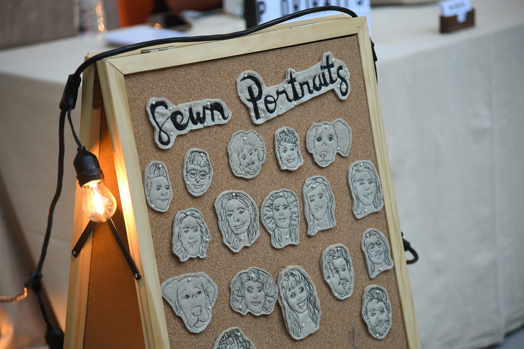 Several sewn portraits by artist Tucker Pierce pinned to a cork board