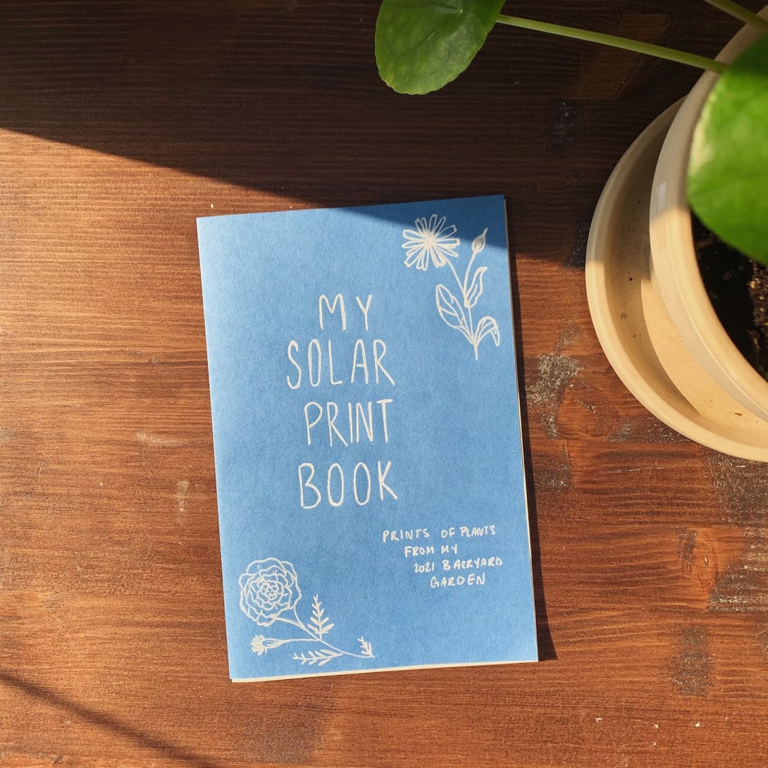 A blue zine sitting on a wooden tabletop. The title of the zine is "My Solar Print Book"