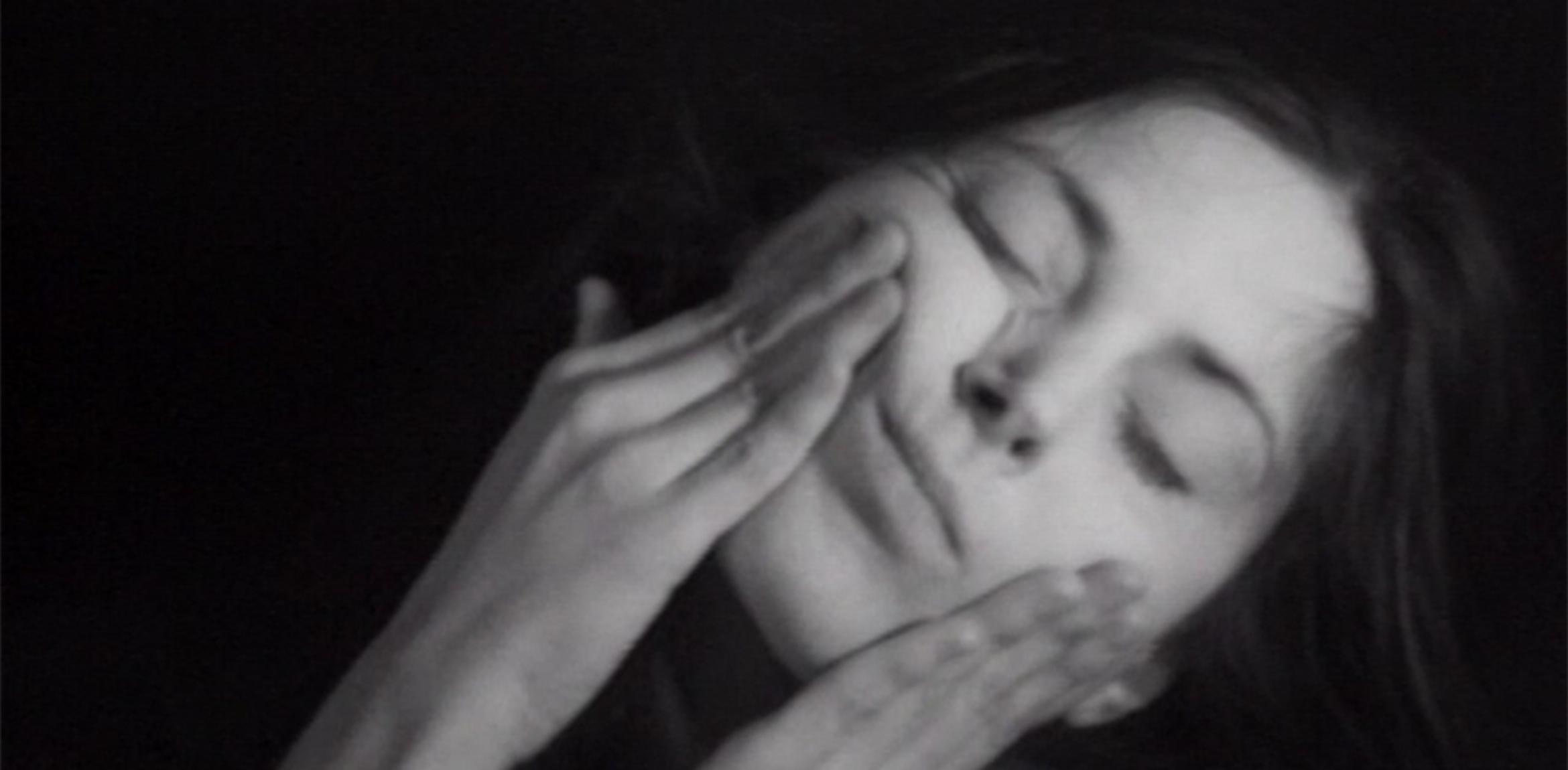 Film still from Hannah Wilke's "Gestures" (1974) in which the artist is shown rubbing her face with her two hands