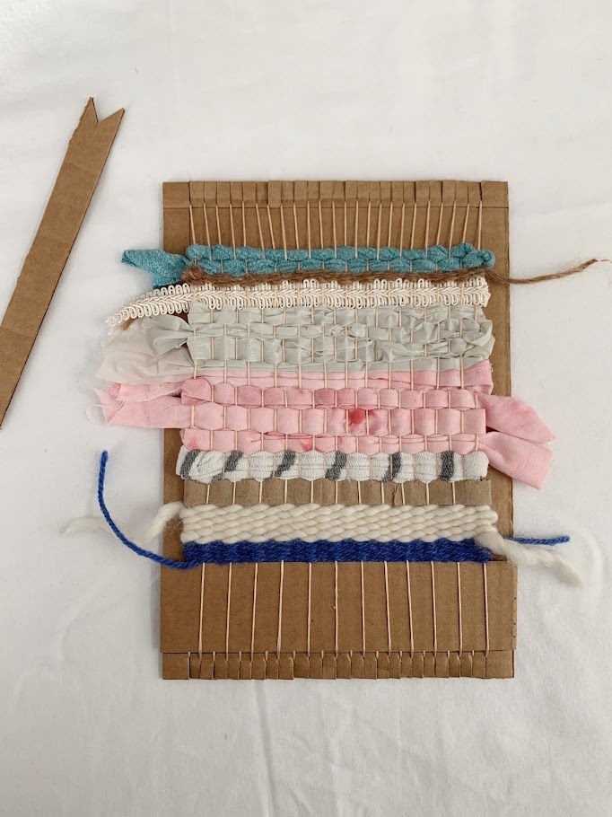 A cardboard loom woven with colorful fibers