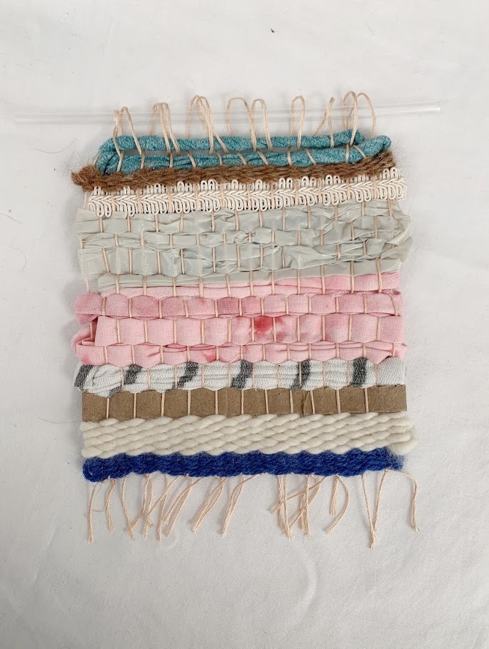 A small, colorful weaving temporarily looped onto a clear straw
