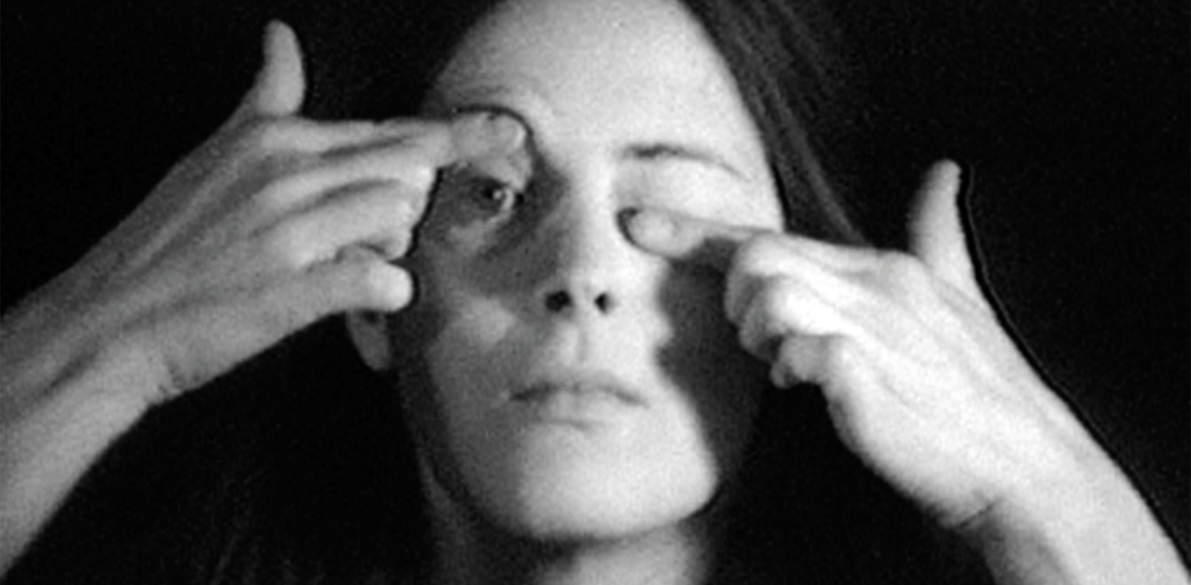 Film still from Hannah Wilke's "Gestures" (1974) in which the artist is shown opening and closing her eyelids with her hands