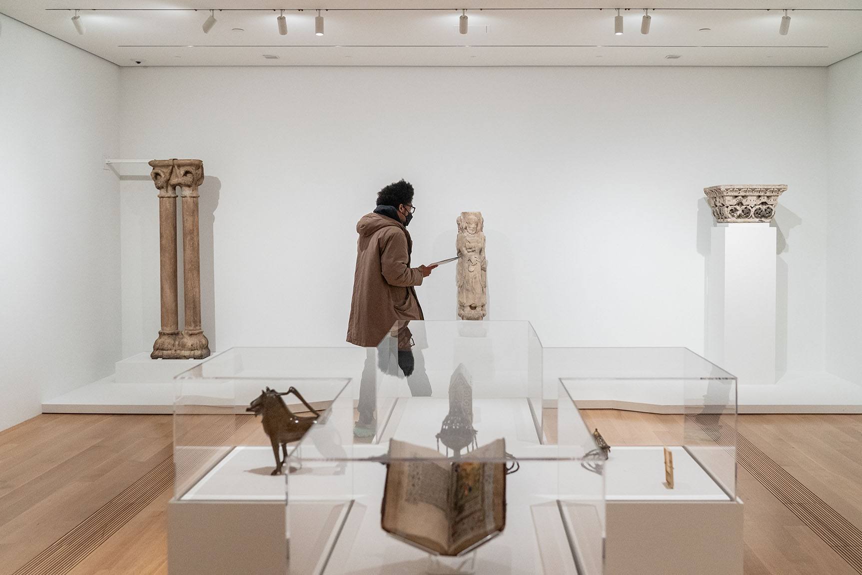 Person going through exhibition looking at stone columns from the middle ages