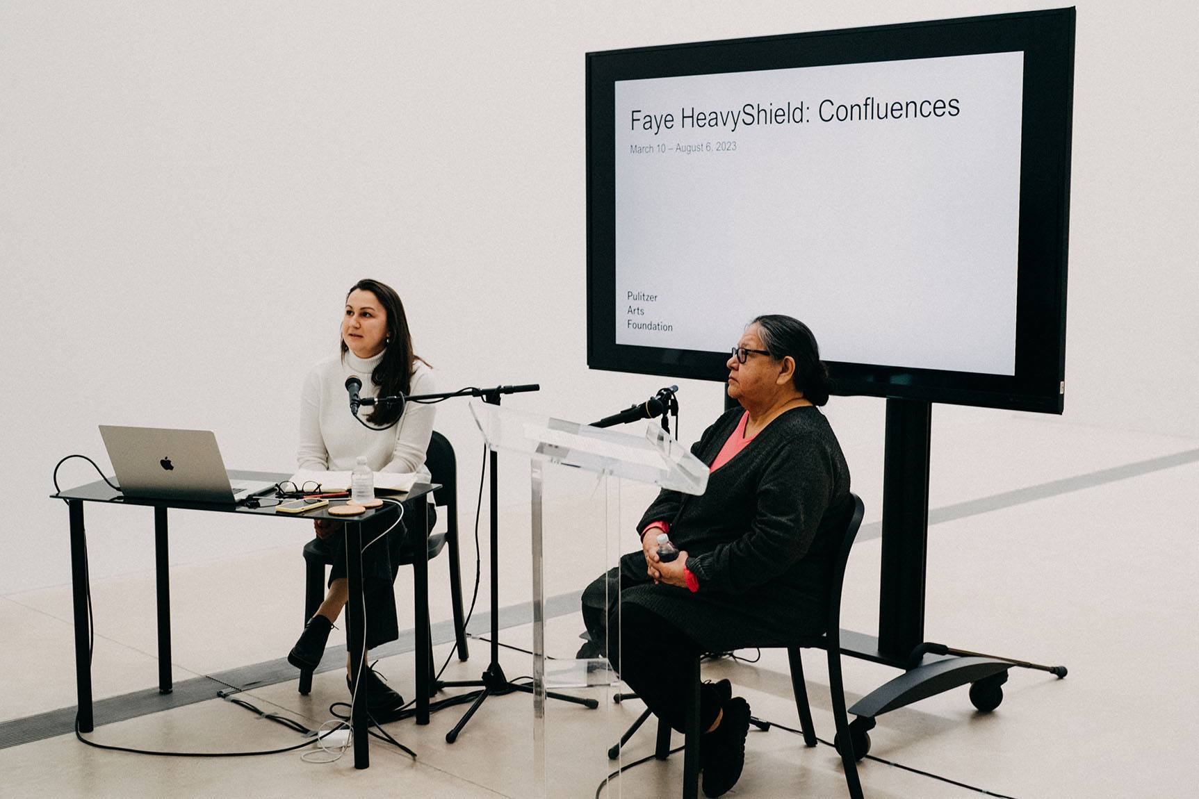 Curator of the Pulitzer, Tamara Schenkenberg and artist, Faye HeavyShield, sitting down speaking to an audience