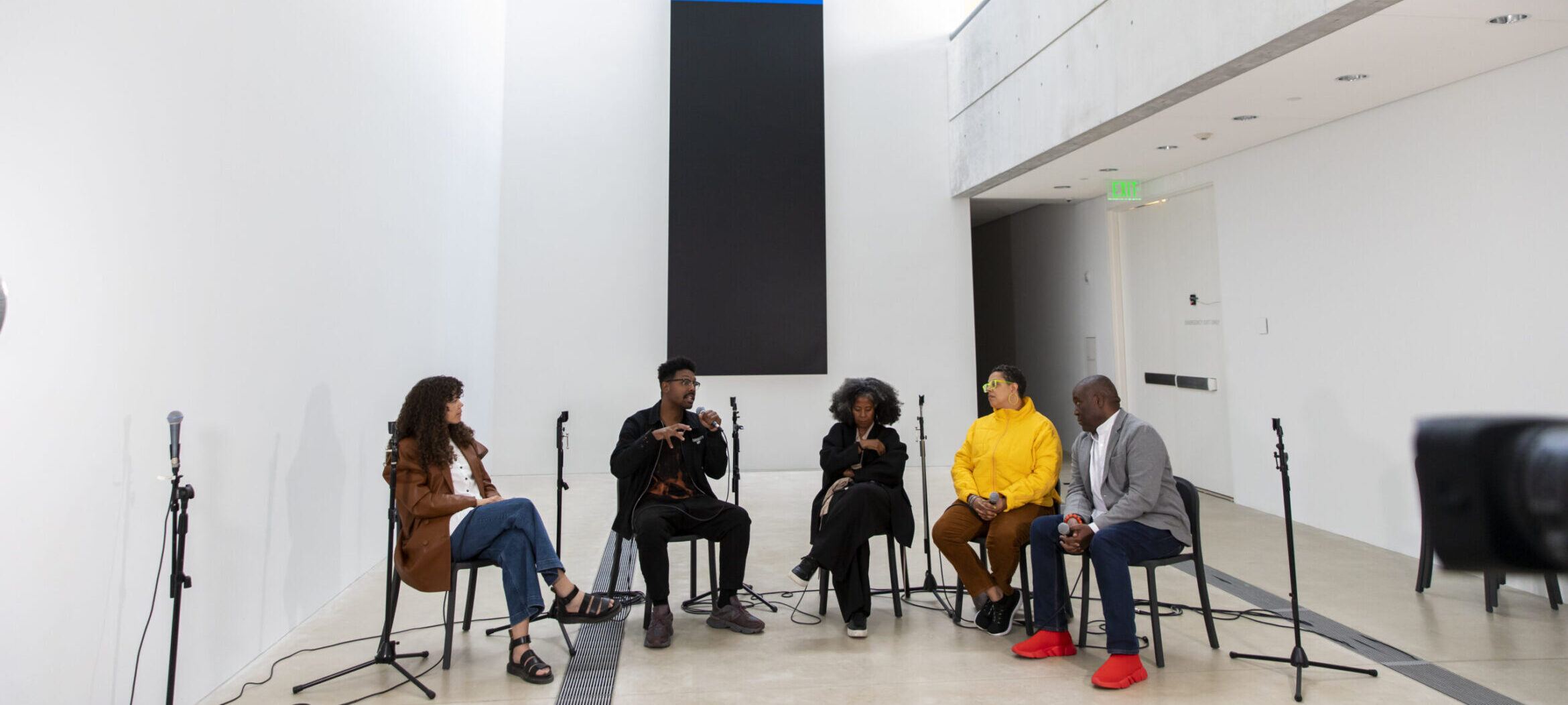 Artists and curators speaking at a roundtable discussion for Counterpublic 2023 in front of Ellsworth Kelly's large vertical blue and black painting.