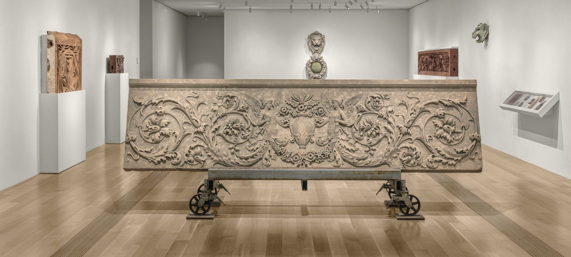 Large horizontal relief sculpture with intricate details of two woman and a bird in the middle, made of limestone.