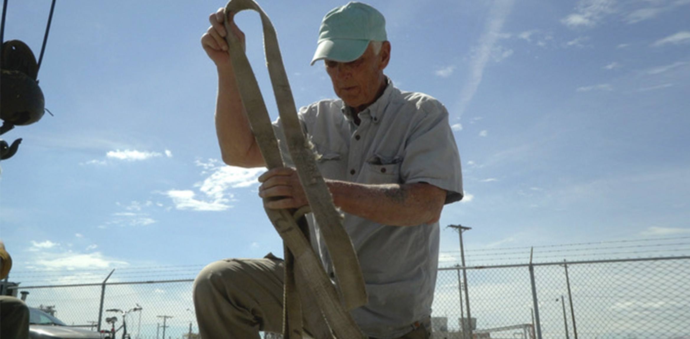 A man tying a thick packing rope with both hands