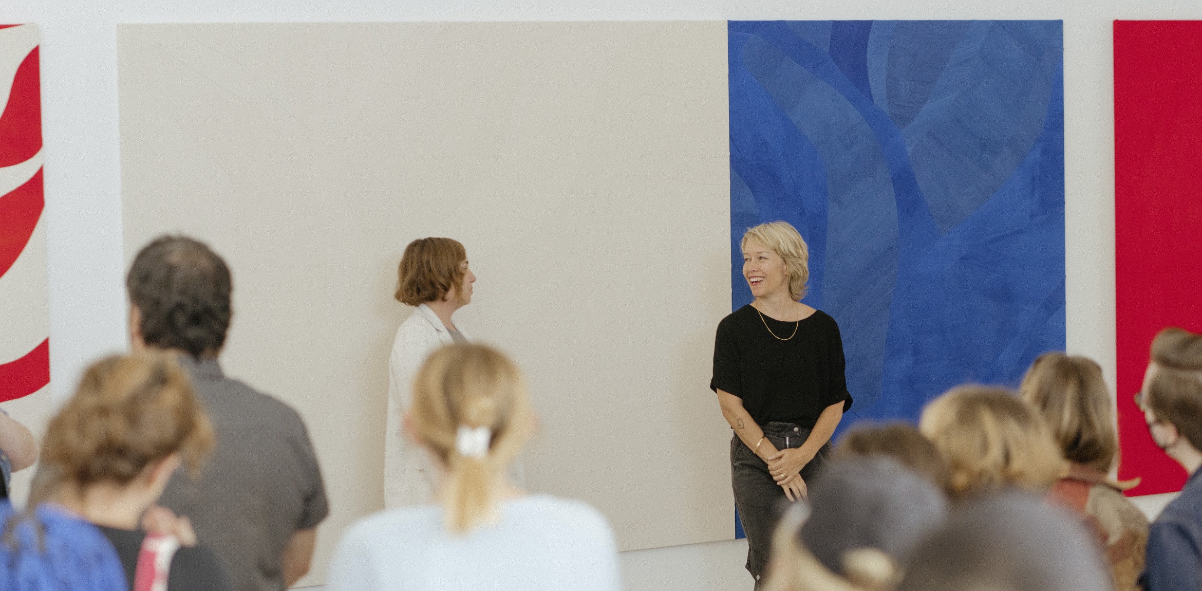 SaraSarah Crowner and Stephanie Weissberg in front of two large crowner paintings while a crowd looks on