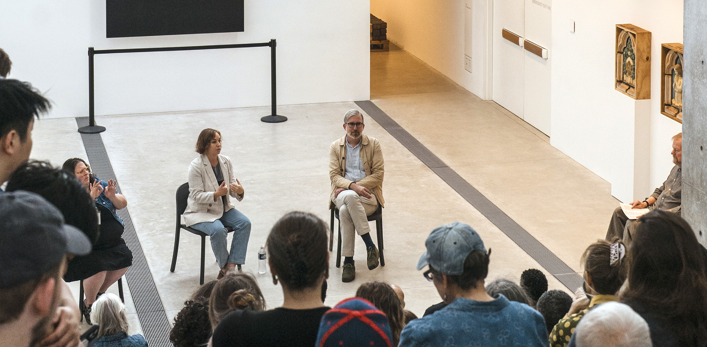 Michael Allen and Stephanie Weissberg seated in front of a crowd in the museum