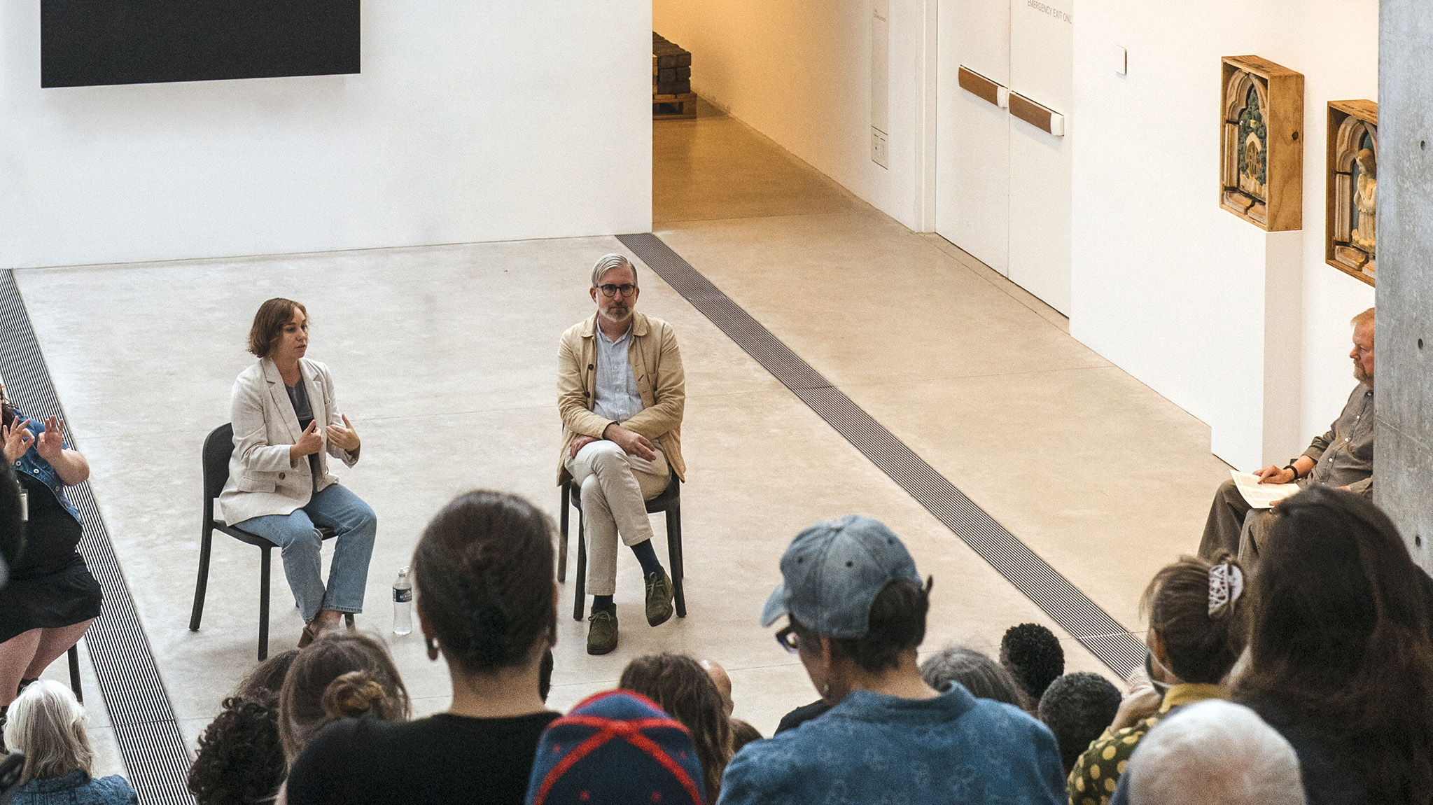 Michael Allen and Stephanie Weissberg seated in front of a crowd in the museum