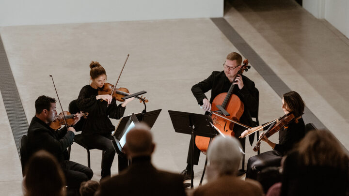 Three violinists and a cellist performing for an audience
